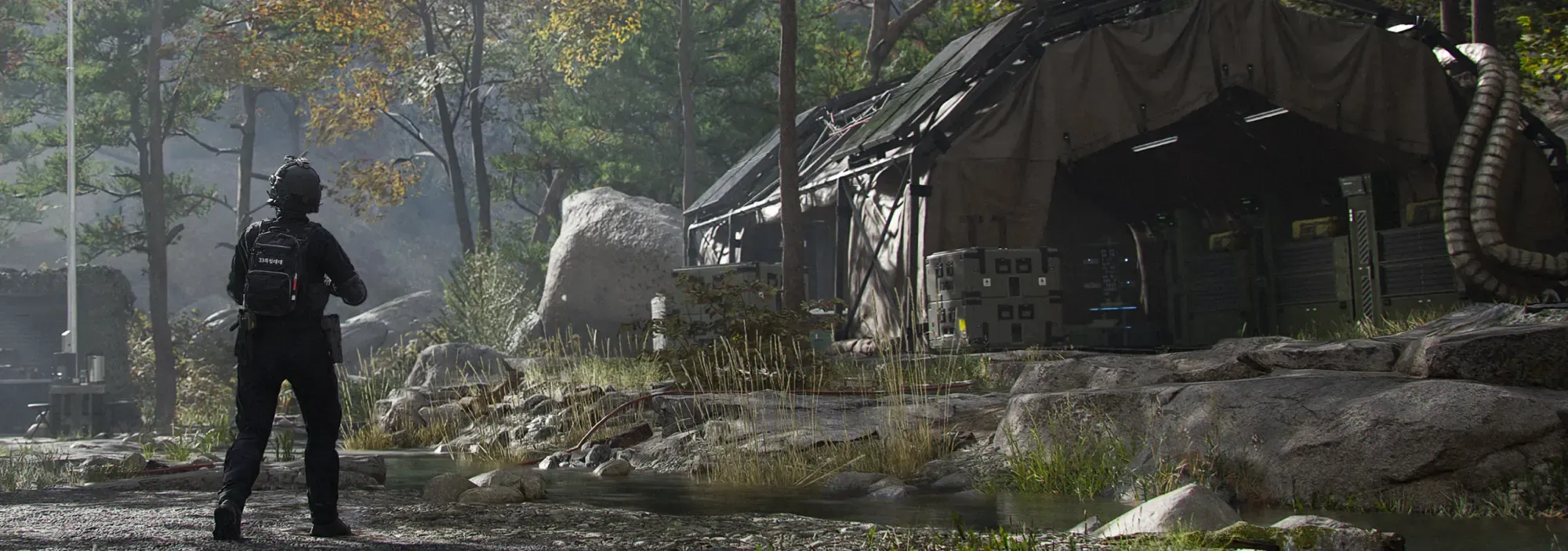 An operator walking toward a forward operating base camp in a forest clearing