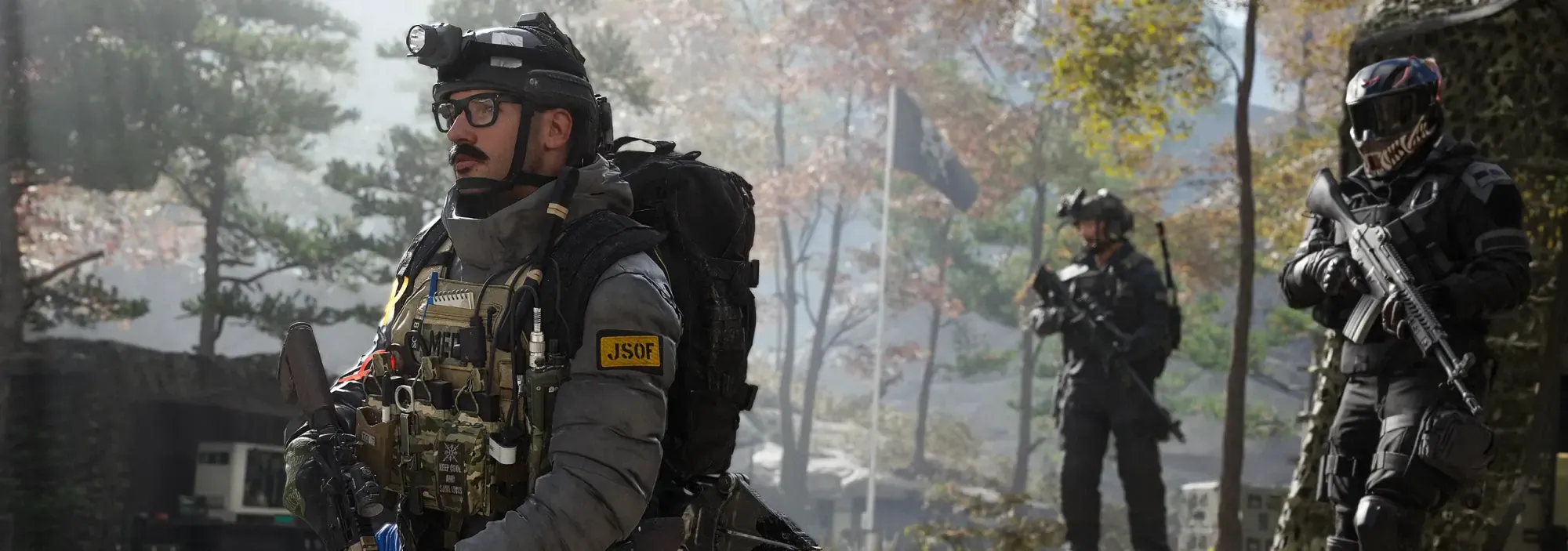 An operator in a heavy pack and helmet gear, teammates holding rifles behind him